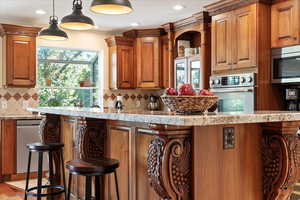 Kitchen featuring appliances with stainless steel finishes, a kitchen breakfast bar, backsplash, plenty of natural light, and recessed lighting