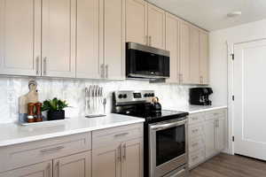 Kitchen featuring appliances with stainless steel finishes, light countertops, backsplash, gray cabinetry, and a textured ceiling