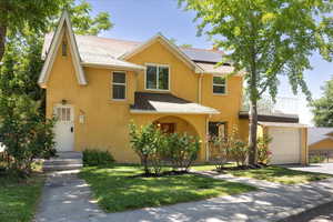 View of front of home with stucco siding, solar panels, a front yard, concrete driveway, and a balcony