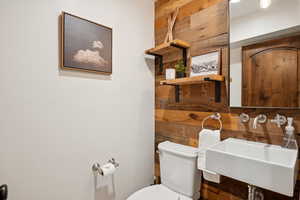 Half bath with toilet and wood walls