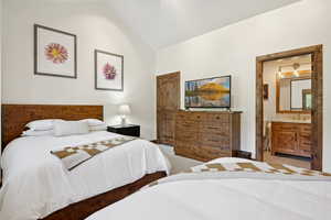 Carpeted bedroom with vaulted ceiling and ensuite bathroom