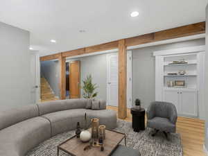 Living area with recessed lighting, light wood finished floors, built in shelves, and stairway