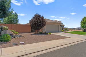 View of front facade with an attached garage, driveway, a tile roof, and stucco siding