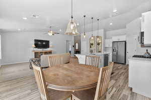 Dining room with vaulted ceiling, a ceiling fan, light wood-type flooring, and recessed lighting