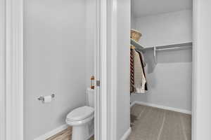 Primary Bathroom featuring toilet and a walk in closet