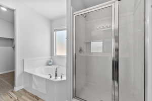 Primary Full bathroom featuring a stall shower, a bath, wood-look tile floors, and a walk in closet