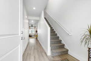 Staircase with wood finished floors and recessed lighting