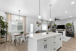 Kitchen featuring light wood finished floors, ceiling fan, recessed lighting, a chandelier, and a kitchen island
