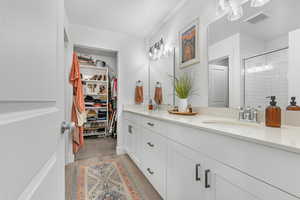 Bathroom featuring double vanity, a stall shower, wood finished floors, and a walk in closet