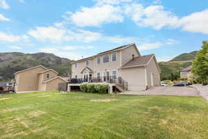 Back of property featuring stairs, a deck with mountain view, and a lawn