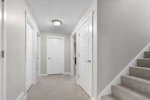 Corridor with light carpet and a textured ceiling