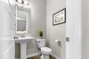 Half bathroom with toilet and wood finished floors