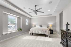 Bedroom with a tray ceiling, light carpet, ceiling fan, and recessed lighting