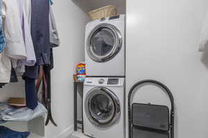 Laundry area with stacked washer and clothes dryer and baseboards