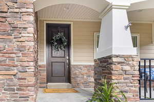 Entrance to property featuring stone siding and covered porch