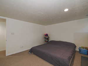 Bedroom with carpet, a textured ceiling, and recessed lighting