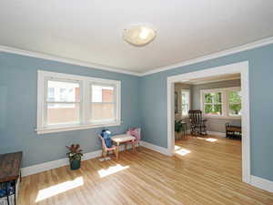 Living area with crown molding and light wood-type flooring
