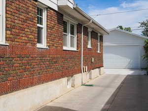 View of side of home with brick siding, an outbuilding, and driveway