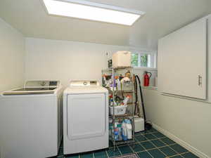 Laundry room with washing machine and clothes dryer and dark tile patterned flooring