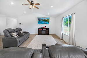 Living room featuring light wood finished floors, vaulted ceiling, ceiling fan, and recessed lighting