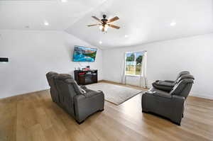 Living room with ceiling fan, vaulted ceiling, light wood-style flooring, and recessed lighting