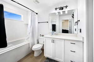Full bath featuring shower / bath combination with curtain, vanity, and wood finished floors