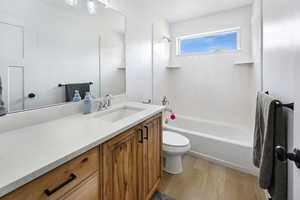 Full bath featuring wood finished floors, vanity, and washtub / shower combination