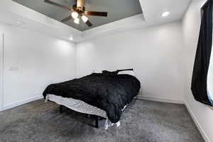 Bedroom featuring a raised ceiling, carpet flooring, recessed lighting, and a ceiling fan
