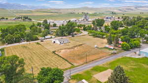 Aerial view of sparsely populated area with rows of crops and mountains