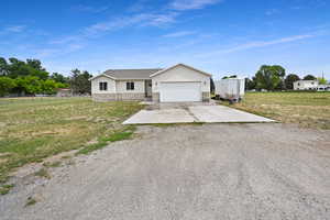 Ranch-style home with stone siding, driveway, a front yard, and a garage