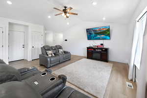 Living area with a ceiling fan, light wood-style flooring, vaulted ceiling, and recessed lighting