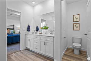 Bathroom featuring ensuite bath, double vanity, and wood finished floors