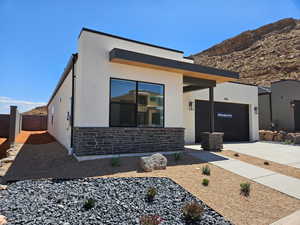 Contemporary house with stone siding, driveway, stucco siding, a garage, and a mountain view