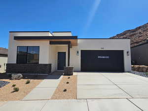 Contemporary house featuring a garage, stucco siding, and driveway