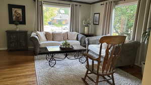 Living area with healthy amount of natural light, wood finished floors, and crown molding