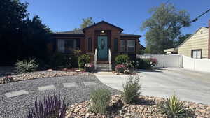 View of front of house featuring concrete driveway, xeriscaped landscaping, a gate, and brick siding