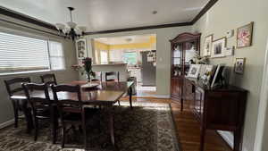 Dining area with a chandelier, crown molding, and wood finished floors