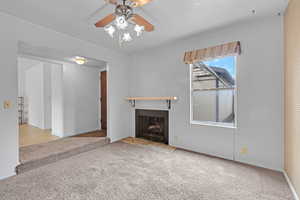 Unfurnished living room with carpet floors, a fireplace with flush hearth, and a ceiling fan