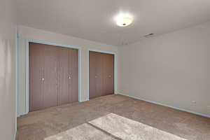 Unfurnished bedroom with carpet, a textured ceiling, and multiple closets