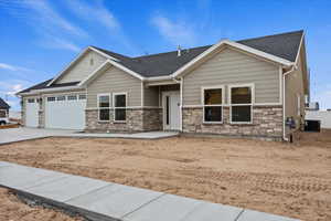 Example of Craftsman house featuring driveway, stone siding, an attached garage, and roof with shingles