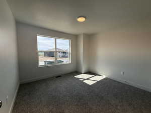 Empty room with carpet flooring and a textured ceiling