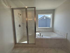 Bathroom with a bath, marble finish flooring, and a stall shower