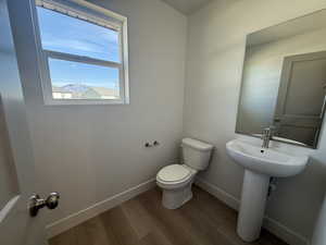Half bathroom with toilet and wood finished floors