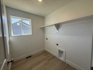 Laundry area featuring washer hookup, electric dryer hookup, wood finished floors, and a textured ceiling