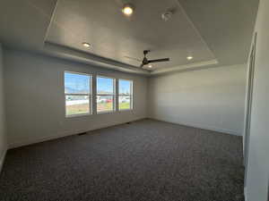 Carpeted spare room featuring a tray ceiling, a ceiling fan, recessed lighting, a textured ceiling, and a smoke detector