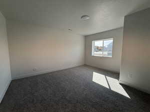Carpeted spare room with baseboards and a textured ceiling