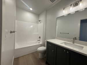 Bathroom with wood finished floors, vanity, and shower / bathtub combination
