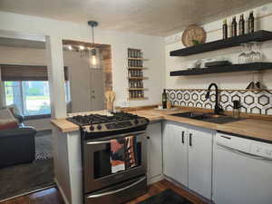 Kitchen featuring butcher block counters, dishwasher, stainless steel gas range, floating shelves, and built-in spice rack