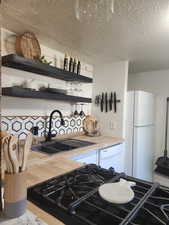 Kitchen with white appliances, designer sink, butcher block countertops