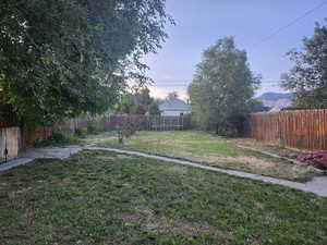 Fenced backyard featuring pathways to garden area and horseshoe pit